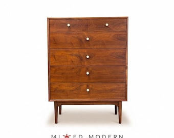 May include: A tall wooden chest of drawers featuring a rich brown wood grain finish. The unit includes two small top drawers and four full-width lower drawers, each accented with a single small white circular knob. It stands on four tapered legs.