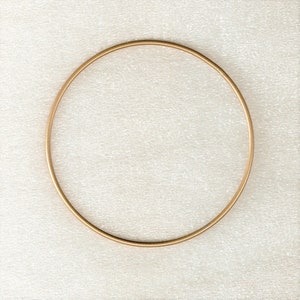 May include: A gold-coloured metal hoop, or circle, on a white textured background.