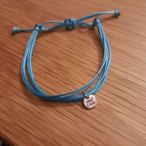 May include: A blue string bracelet with a silver charm that says "still i rise".