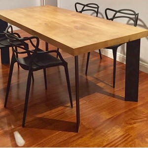 May include: A wooden dining table with a natural finish and black metal legs. Four black chairs with a unique design surround the table.