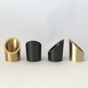 May include: Four small, angled, cylindrical holders in gold, black, and silver.