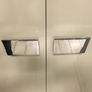 May include: Two silver rectangular cabinet door handles with a brushed finish.