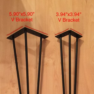 May include: Two black metal V-shaped brackets for furniture legs. The larger bracket measures 5.90" x 5.90" and the smaller bracket measures 3.94" x 3.94".