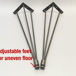 May include: Two silver metal table legs with adjustable feet. The legs are made of four metal rods that are connected at the top and bottom. The feet are round and have a black rubber coating.
