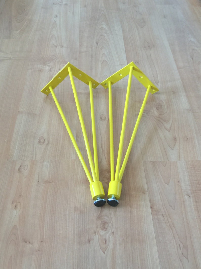 May include: Two yellow metal table legs with a triangular base and five prongs each. The legs have black rubber feet.