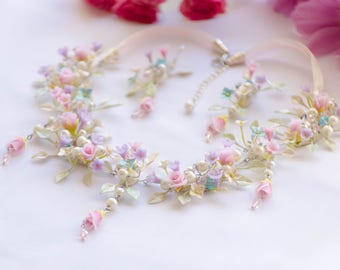 May include: A delicate floral necklace and earrings set with pastel pink, purple, and blue flowers, accented with white pearls and silver leaves.
