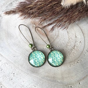 Peut inclure: Une paire de boucles d'oreilles pendantes avec des perles de verre vertes et des cabochons ronds à motifs verts et blancs.