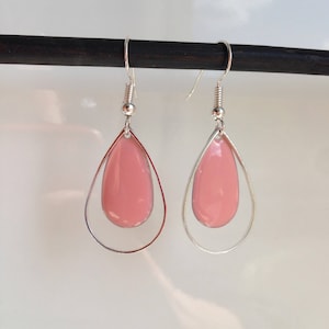 Könnte beinhalten: Ein Paar silberne Ohrringe mit rosa tropfenförmigen Steinen. Die Ohrringe haben ein schlichtes, elegantes Design.