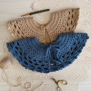 May include: Two crocheted collars, one beige and one blue, laid out on a white crocheted doily.