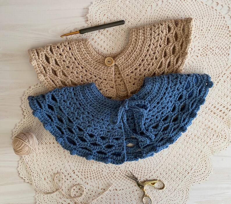May include: Two crocheted collars, one beige and one blue, laid out on a white crocheted doily.