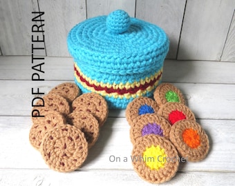 May include: A crocheted blue container with a lid and a red and yellow stripe. Several crocheted cookies are arranged around the container. Some cookies have colorful centers. The text "PDF PATTERN" is on the left side of the image.