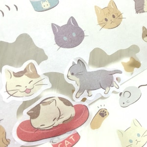Puede incluir: Una hoja de pegatinas con varias ilustraciones de gatos. Las pegatinas son blancas con una superposición translúcida. Los gatos se representan en diferentes poses, incluyendo dormir, caminar y sentarse. Algunas de las pegatinas tienen un fondo marrón claro.