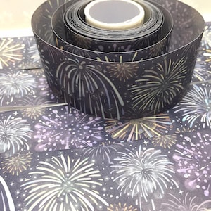 Può includere: Un rotolo di nastro washi nero e bianco con un motivo di fuochi d'artificio. Il nastro è arrotolato su un nucleo bianco e ha una finitura olografica argentata.