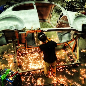 Photograph of WELDER working on Volkswagen Beetle, industrial photos, VW photography, mechanic, auto shop, classic cars, amazing photographs