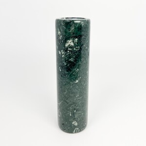 Könnte beinhalten: Eine zylindrische, dunkelgrüne Marmorvase mit weißen Adern. Die Vase hat eine glatte, polierte Oberfläche und ein schlichtes, elegantes Design. Die Vase ist etwa 15 cm hoch.