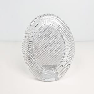 May include: A clear glass oval picture frame with a textured, wavy design. The frame is made of thick glass and has a smooth, polished finish.