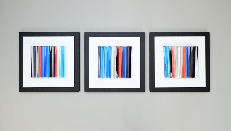 Pu&ograve; includere: Tre pezzi di arte da parete incorniciati con motivi a mosaico di vetro colorati. Ogni pezzo presenta una disposizione verticale di bacchette di vetro in tonalit&agrave; di blu, rosso, bianco e nero.