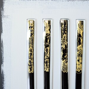 May include: Six black and gold glass panels with a decorative pattern. The panels are mounted on a white background.