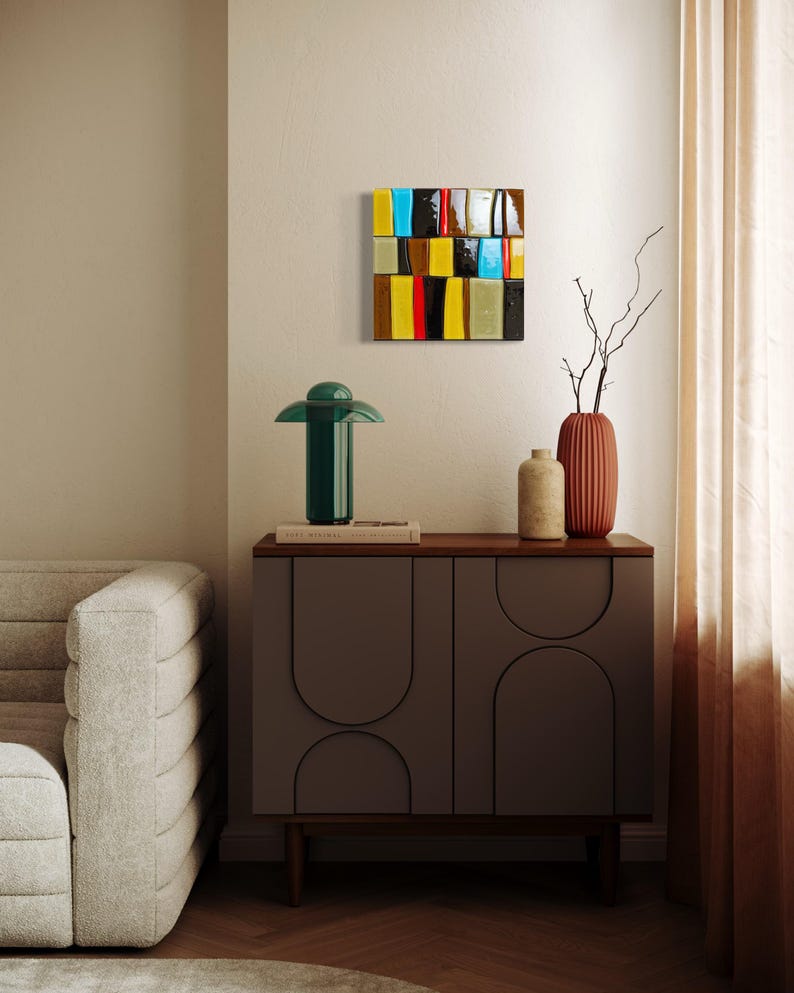 May include: A contemporary living room with a dark green table lamp, a grey cabinet, and a colourful abstract wall art piece. The artwork features rectangular blocks in various colours. A sofa and decorative vases complete the scene.