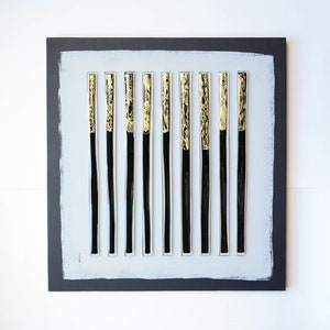 May include: A black and gold abstract wall art piece with 12 vertical glass tubes on a gray background.