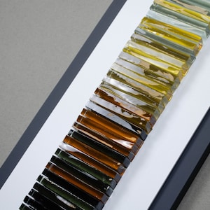 May include: A framed wall art piece featuring a gradient of glass tiles in shades of green, yellow, and brown.
