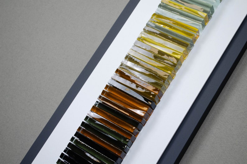 May include: A framed wall art piece featuring a gradient of glass tiles in shades of green, yellow, and brown.