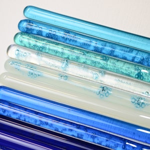 Pu&ograve; includere: Un set di dieci bacchette di vetro in varie tonalit&agrave; di blu, dal blu scuro al blu chiaro, con bolle d'aria intrappolate al loro interno. Le bacchette sono disposte in un motivo sfumato, con il blu pi&ugrave; scuro in basso e il blu pi&ugrave; chiaro in alto.