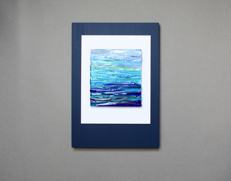 May include: A framed abstract art piece with a blue and white color scheme. The artwork is made of layered glass and resembles a seascape.