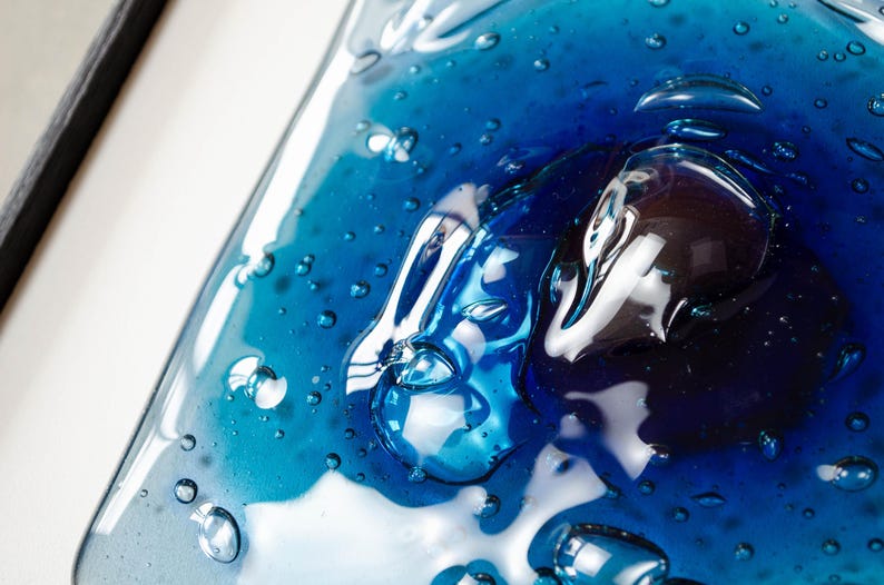 May include: A rectangular glass plate featuring a gradient of deep cobalt blue to lighter turquoise tones. The surface is characterized by numerous trapped air bubbles of varying sizes, creating a textured, liquid-like appearance with high gloss.