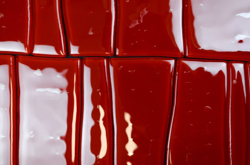 May include: Close-up of a glossy, rectangular tile pattern. Alternating red and white tiles create a striking visual effect. The tiles are arranged in a grid, with dark lines separating each piece. The reflective surface enhances the vibrant colours.