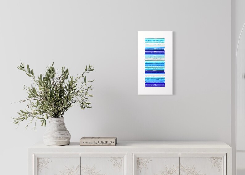 Pu&ograve; includere: Stampa d'arte astratta con una disposizione verticale di strisce blu e turchesi su uno sfondo bianco.