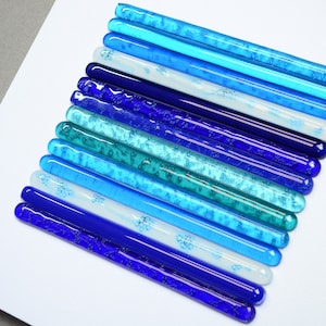 May include: A wall art piece made of glass rods in various shades of blue, from teal to dark blue, arranged in a graduated pattern.