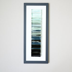May include: A framed wall art piece featuring a vertical gradient of glass tiles in shades of blue, green, and black.