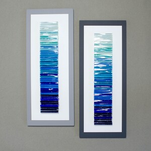 May include: Two framed pieces of art with a gradient of blue glass tiles. The tiles are arranged vertically in a graduated pattern from light blue to dark blue.