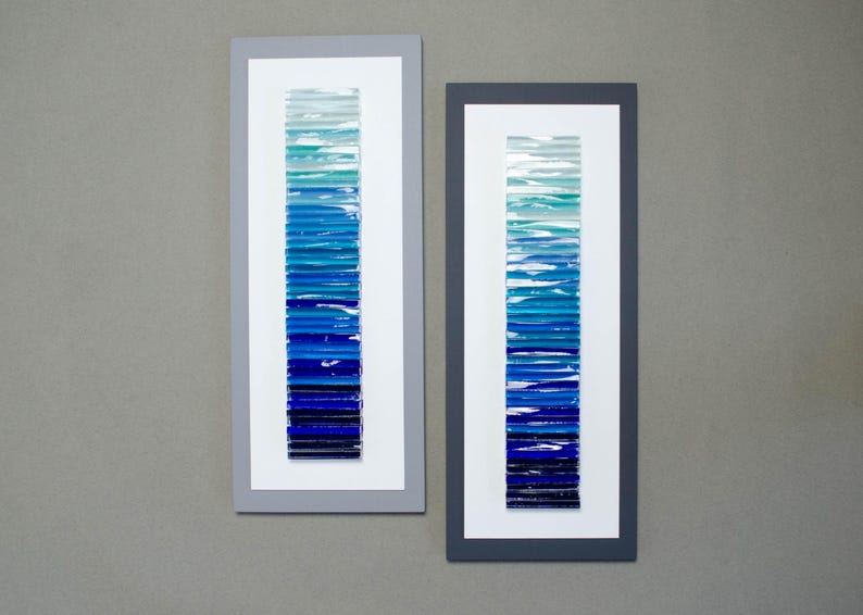 May include: Two framed pieces of art with a gradient of blue glass tiles. The tiles are arranged vertically in a graduated pattern from light blue to dark blue.