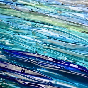 May include: Abstract glass art piece with a layered design of blue, green, and white glass. The glass is textured and has a wavy appearance.