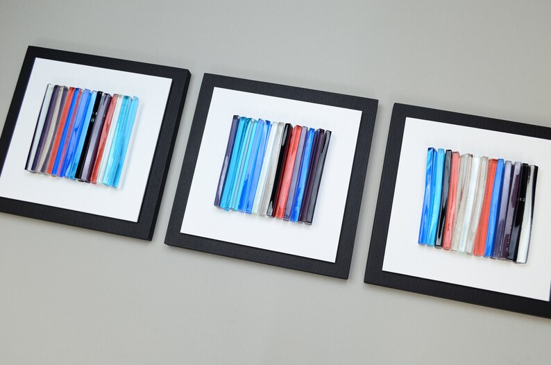 Pu&ograve; includere: Tre pezzi di arte da parete incorniciati con bacchette di vetro colorate disposte in linee verticali. Le bacchette di vetro sono in tonalit&agrave; di blu, rosso, bianco e nero.