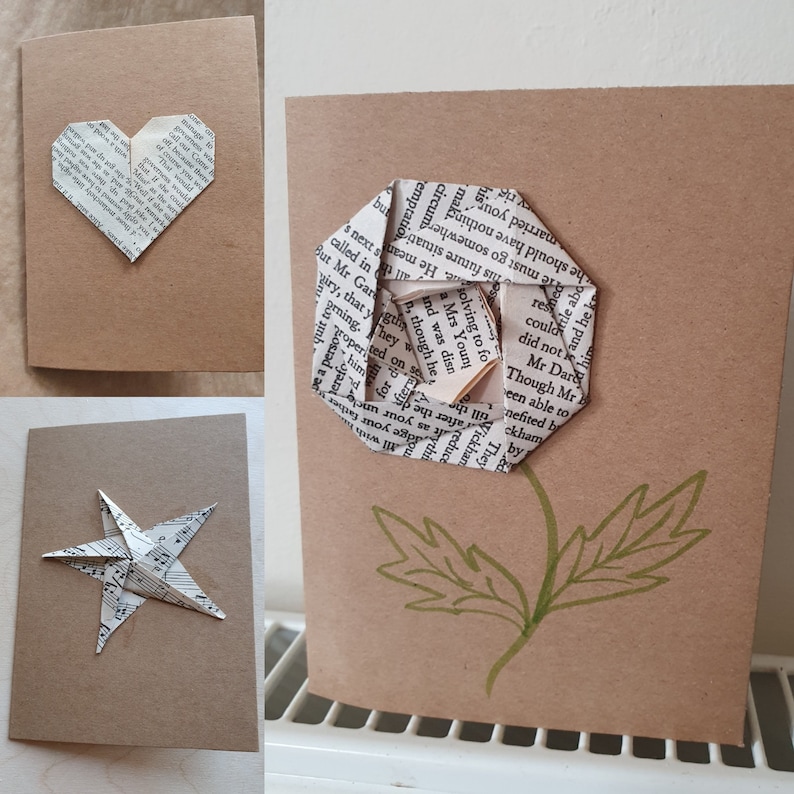 Op de afbeelding: Drie handgemaakte kaarten met origami-bloemen gemaakt van boekpagina's. De kaarten zijn bruin en hebben een rustieke uitstraling. De bloemen zijn een hart, een ster en een roos.