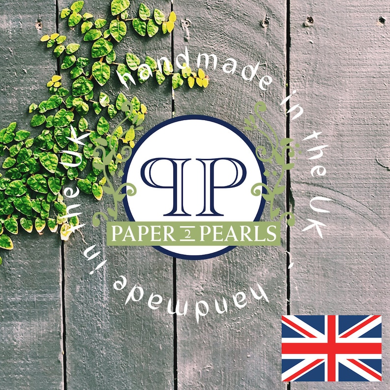 Op de afbeelding: Een witte cirkel met de letters "QP" in blauw en de tekst "PAPER & PEARLS" in zwart. De cirkel is omgeven door de tekst "Handmade in the UK" in wit op een grijze houten achtergrond met groene wijnstokken.