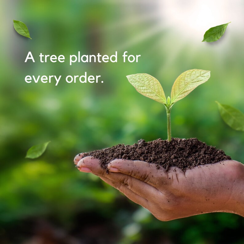 Op de afbeelding: Een hand houdt een kleine groene plant vast met twee bladeren die uit donkerbruine aarde groeien. De achtergrond is wazig en groen. De tekst "A tree planted for every order." staat in de linkerbovenhoek van de afbeelding.