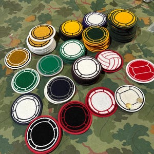 Può includere: Una collezione di toppe rotonde ricamate in vari colori, tra cui giallo, verde, bianco e rosso. Alcune toppe presentano disegni di palloni sportivi, mentre altre hanno un centro a tinta unita con un bordo a contrasto. Le toppe sono impilate e sparse.