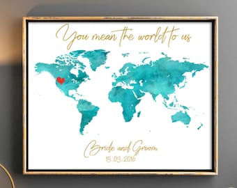 May include: A watercolor world map print with a red heart marking a location on the map. The print has a gold frame and the text "You mean the world to us" and "Bride and Groom 15.03.2016" in gold lettering.