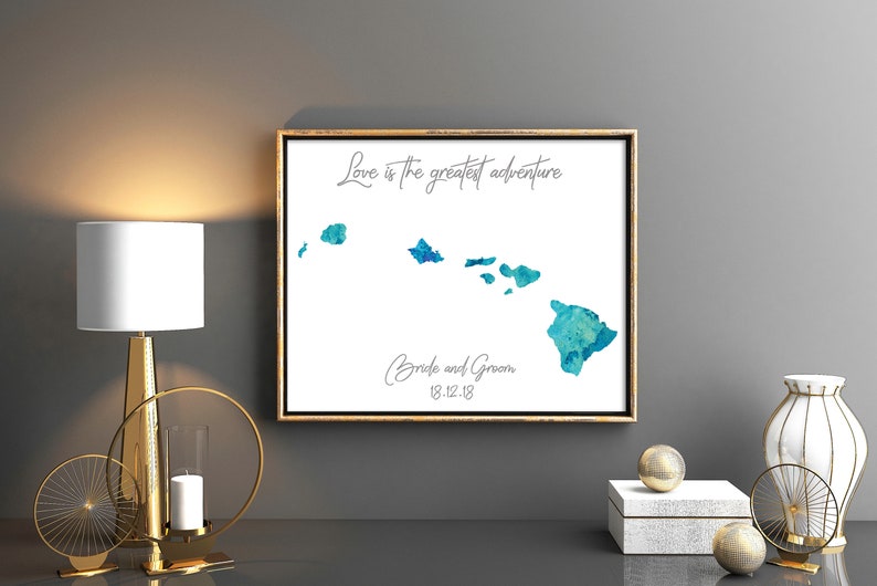 May include: A watercolor painting of the Hawaiian islands with the text "Love is the greatest adventure" and "Bride and Groom 12.12.18" in a gold frame.