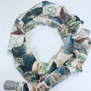 May include: A fabric hose cover with a patchwork design. The cover features a repeating pattern of winter scenes in shades of blue, beige, and brown. The design includes images of houses, animals, and botanical elements.