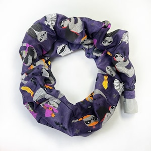 May include: Purple fabric headband with a Halloween-themed print featuring various cartoon sloths dressed in costumes. The print includes bats, stars, and moons.
