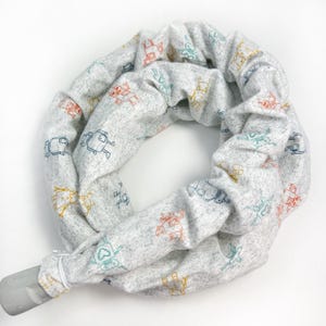 May include: A gray fabric tube with a zipper closure. The fabric has a repeating pattern of small robots in various colors, including blue, orange, and yellow.