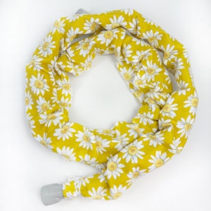 May include: A yellow fabric headband with a white daisy print. The headband is tied in a knot at the back.