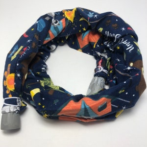 May include: A blue fabric tube with a camping theme print. The tube has a white elastic band at each end and a gray plastic end cap. The print features tents, stars, trees, and the words "Camp Fun".