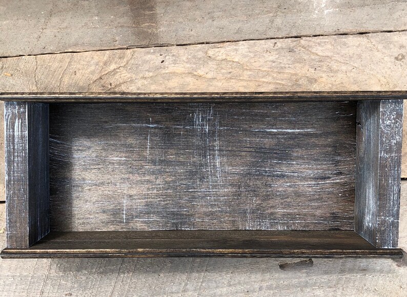 May include: A dark wood rectangular box with a distressed finish. The box has a raised lip around the edge and is empty.