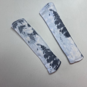 Pu&ograve; includere: Due coperture in tessuto rettangolari con un motivo tie-dye in tonalit&agrave; grigio antracite scuro e azzurro. Ogni pezzo ha estremit&agrave; arrotondate e un bordo cucito visibile, con un aspetto morbido e strutturato.